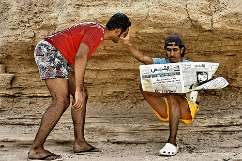 man reading the paper smacks another man in the face