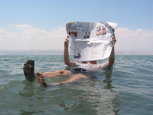 Man reading a newspaper while floating in the Dead Sea